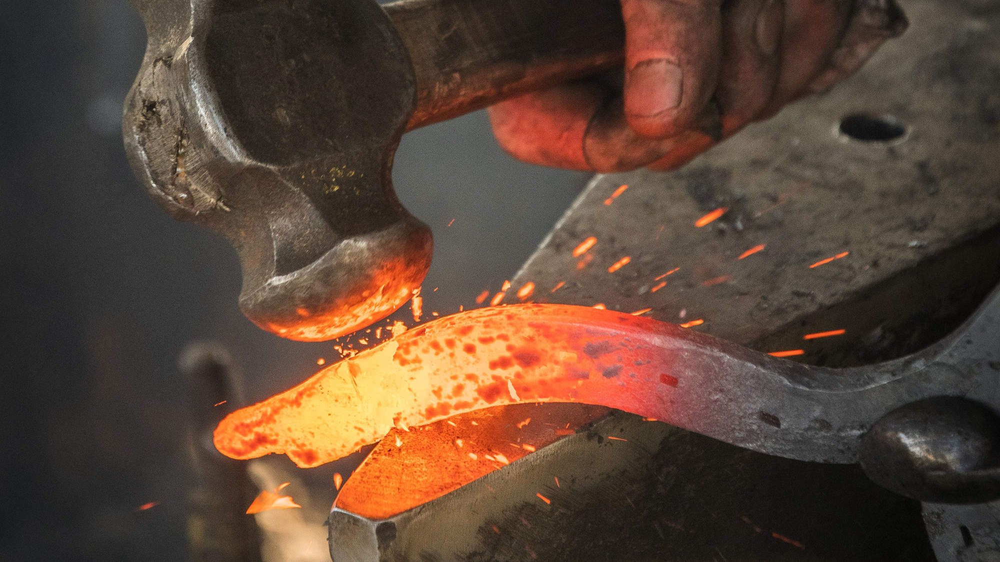 Hammer hitting an anvil. Sparks fly as the tool hits the hot iron.