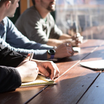 A group of people participating in a workshop situated in a light filled room on a higher storey.