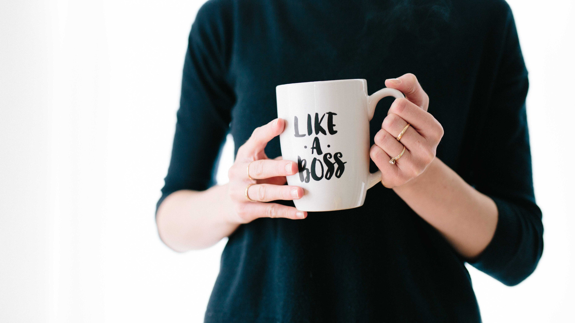 Woman holding a coffee mug which quotes "Like a boss"