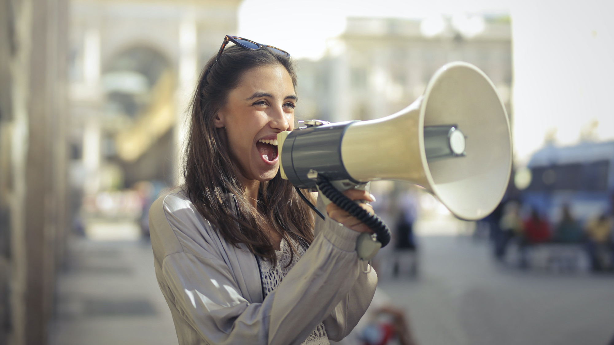 Woman standing on the street and using a megaphone for an announcement