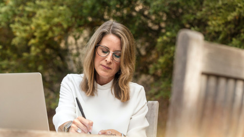 Woman sitting at a table in the garden writing something down