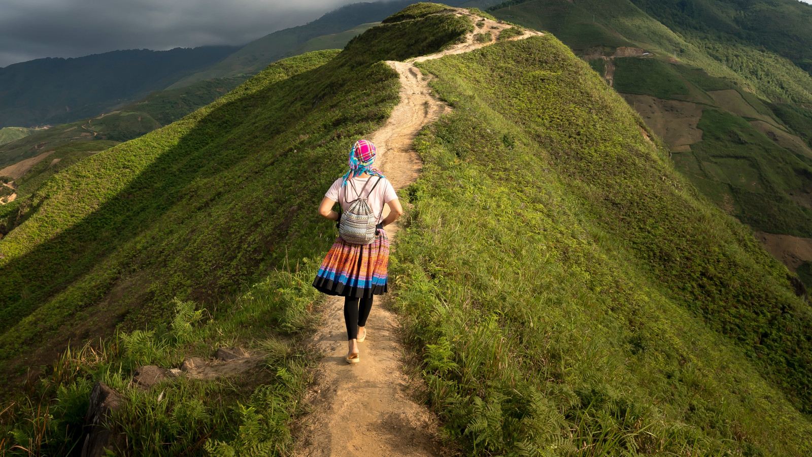 Eine Frau wandert auf einem Pfad einen Berg hinauf.